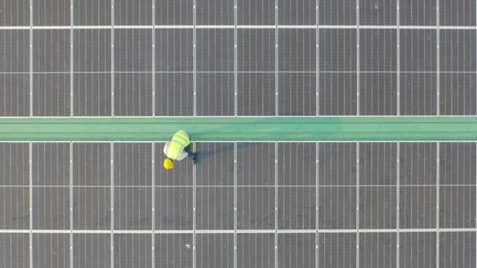 在工厂工业中，屋顶上有太阳能电池板或太阳能电池的工程师或工人，人的空中俯视图。发电厂，可再生能源。电