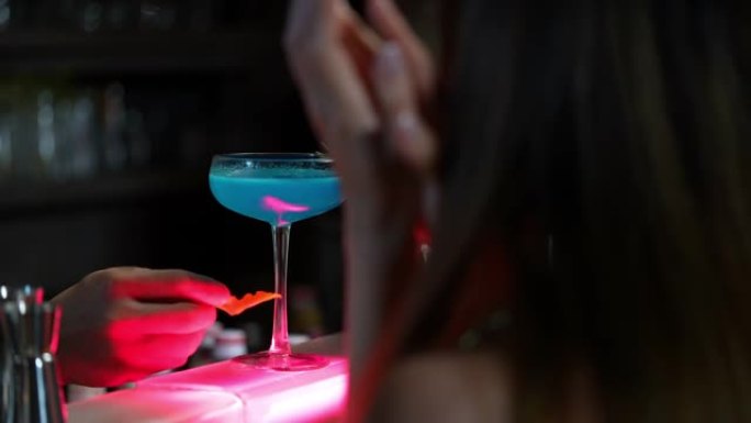 4k亚洲酒保将酒精鸡尾酒饮料倒入装饰鸡尾酒杯中。