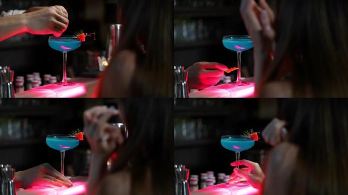 4k亚洲酒保将酒精鸡尾酒饮料倒入装饰鸡尾酒杯中。