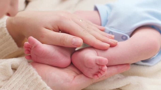 女人的特写镜头用手轻轻抚摸着她刚出生的小儿子的小脚，皮肤完美。家庭幸福与有小孩的父母的观念