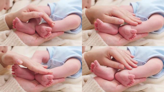 女人的特写镜头用手轻轻抚摸着她刚出生的小儿子的小脚，皮肤完美。家庭幸福与有小孩的父母的观念