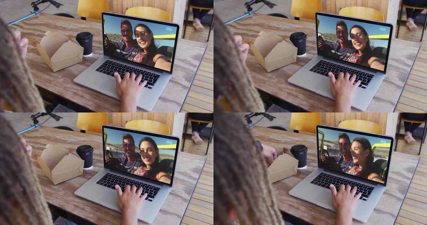 混血男子坐在咖啡馆里，用笔记本电脑与朋友进行视频通话