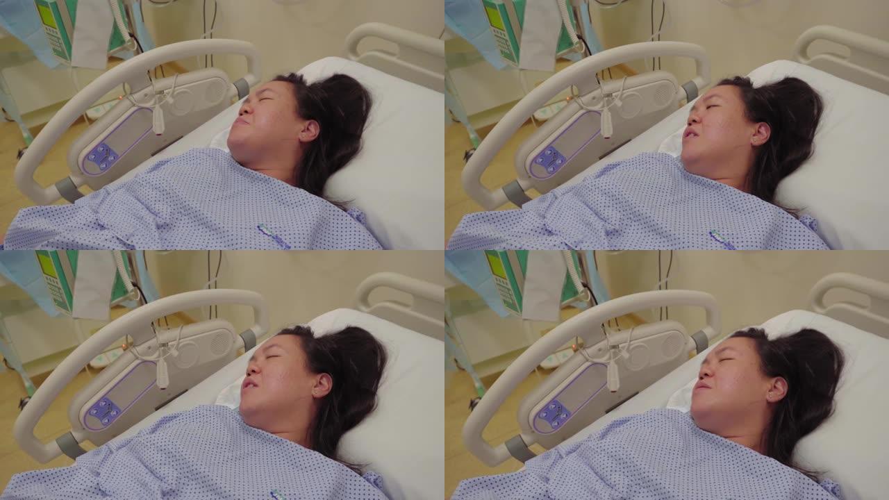 年轻的亚洲华裔女士在医院病床上收缩疼痛等待分娩