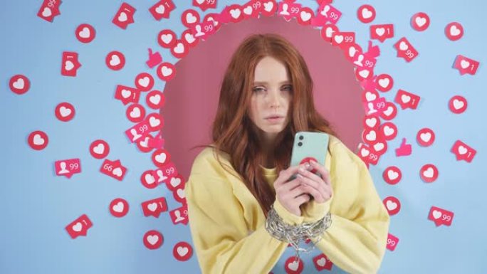 手机拴在女人的手上，网瘾。蓝色背景上的红发女人