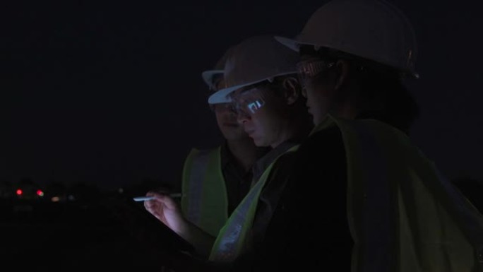 团队工程师或其他专业人员在石油和天然气或其他工业现场工作的视频，晚上使用数字平板电脑工作