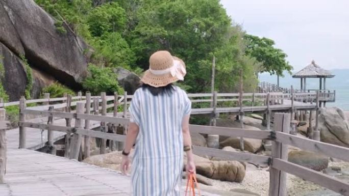 暑假在海上的自然木板路上行走的亚洲妇女