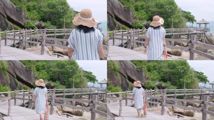 暑假在海上的自然木板路上行走的亚洲妇女