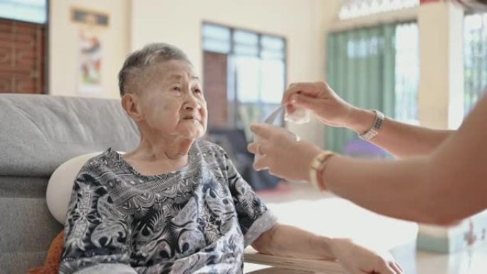亚洲妇女照顾奶奶在家给残疾的亚洲人服药奶奶