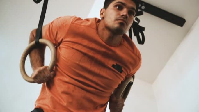 一名运动男子在健身房的体操环上锻炼