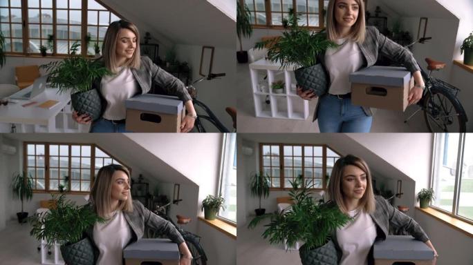 快乐的年轻女子带着植物和盒子搬进了新的家庭办公室设置