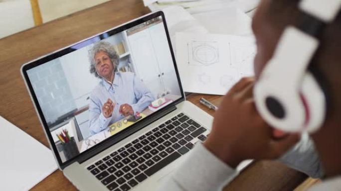 非裔美国男大学生戴着耳机在家里的笔记本电脑上进行视频通话