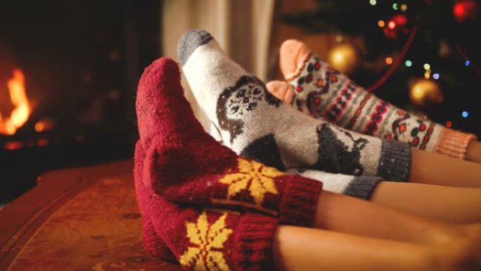 在圣诞节或新年之夜，一对有孩子的夫妇躺在壁炉旁，穿着温暖的羊毛袜的特写镜头。人们在寒假和在家庆祝活动