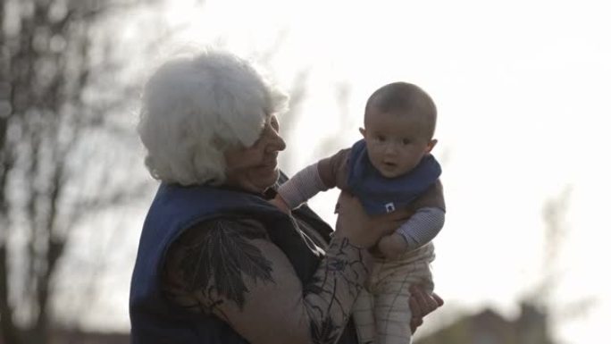 祖母带着婴儿在日落时走在户外。