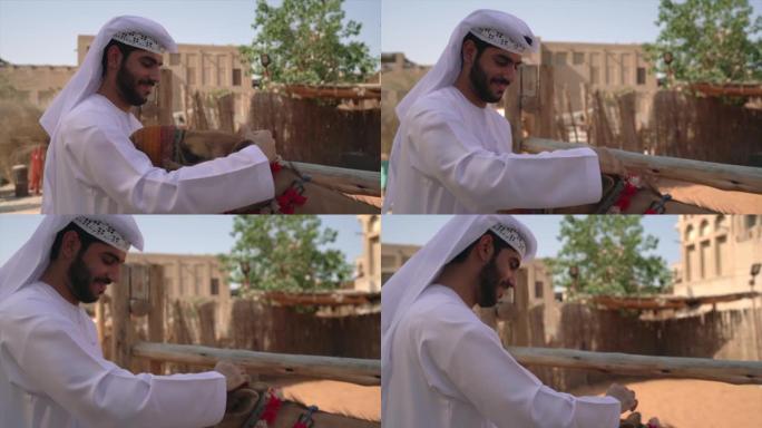 阿拉伯男子穿着传统服装抚摸小骆驼