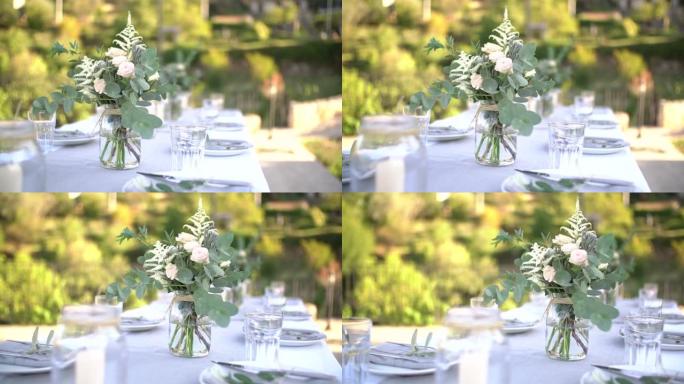 婚礼宴会期间，节日餐桌上的罐子里有玫瑰花、落叶松、科塔德里亚和桉树树枝花束