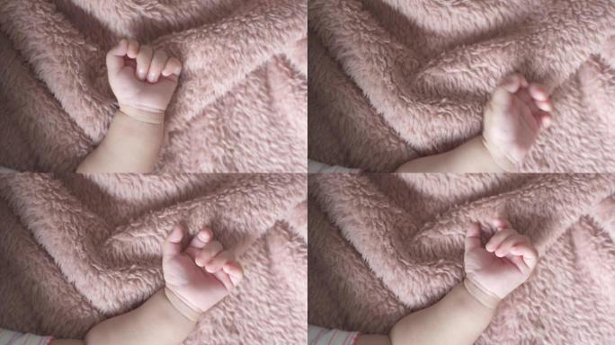 睡觉时，将婴儿手放在柔软的毛毯背景上。