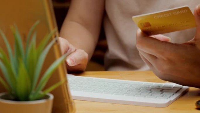 成人的双手填写信用卡号以结清账单或在家在线购物，生活方式概念。