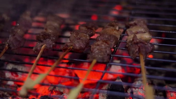 特写街头食品销售商正在烤串上烧烤牛肉。