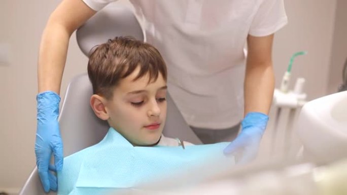 一个小男孩在治疗他的牙齿，两名牙医检查他的牙齿