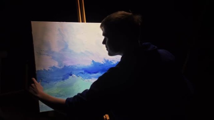 艺术家抄写员用海洋中的船绘制海景。工匠装饰师在蓝色的海上航行时绘制丙烯酸油色。画笔，刀调色板。