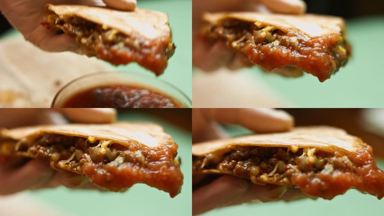 新鲜油炸的热牛肉饼浸泡在莎莎酱中。制作墨西哥玉米饼的过程。宏观视图
