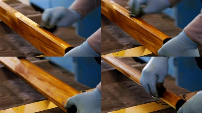 戴着手套的木匠用棕色清漆在木质表面上漆