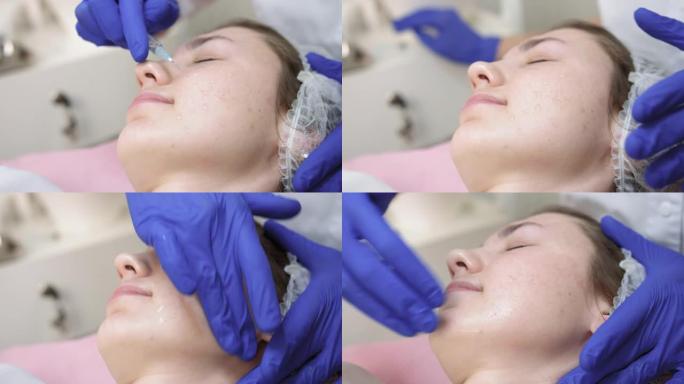 美容师医生的手将注射器中的抗衰老油精滴在女人脸上。面部抗皱护肤。美容诊所年轻女子的特写，进行美容手术