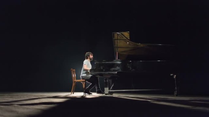 一位现代经典钢琴家在黑色舞台上弹奏钢琴