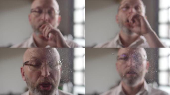 男子在慢动作中喷嚏的细菌和唾液溅到相机的镜头上