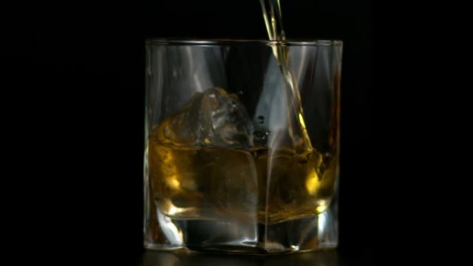 在黑暗背景下将威士忌倒入玻璃中，并加冰的慢动作