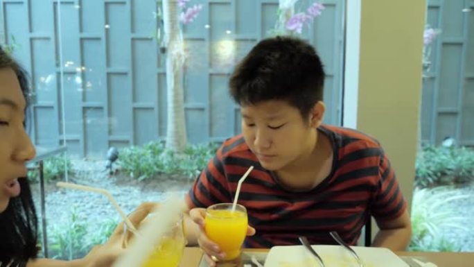 快乐的亚洲儿童在度假旅行期间在酒店的自助餐厅附近欢呼他们的饮料，生活方式理念。