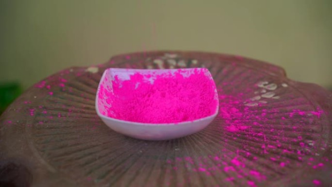 在白色碗里溅出颜色。粉红色的玫瑰花古拉落在碗里。草药有机古拉尔粉庆祝胡里节。