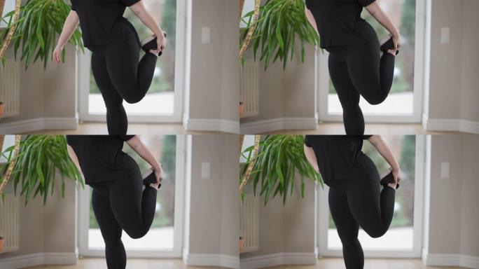 无法辨认的肥胖女运动员伸展腿部肌肉在室内锻炼。年轻的加大码白人妇女早上在家训练。运动锻炼与健康生活方