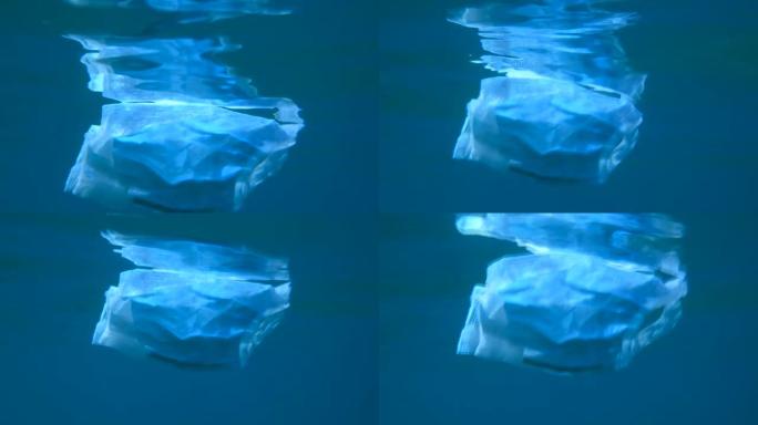 废弃的医用口罩在水面下缓慢漂移。冠状病毒新型冠状病毒肺炎正在造成污染，因为废弃的二手口罩会污染海洋和