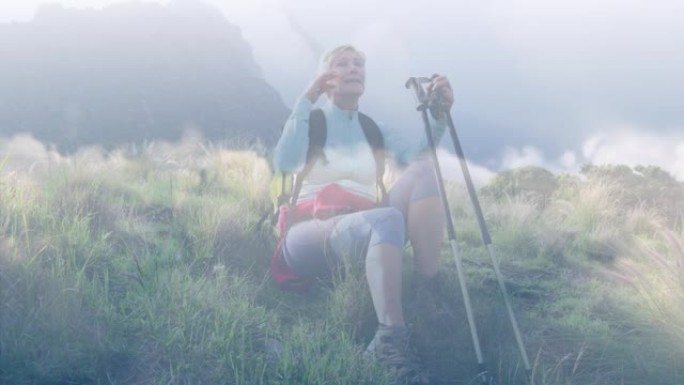 快乐的高加索高级妇女在山上徒步旅行时，在快速移动的云层上休息