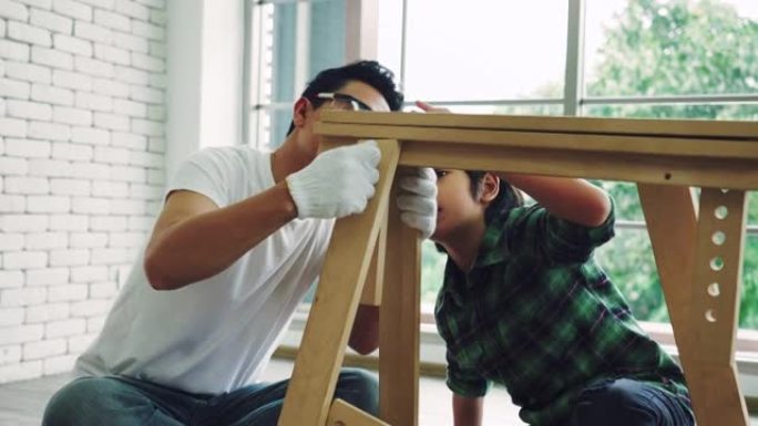 亚洲男人和儿子正在帮助组装房子里的橱柜。