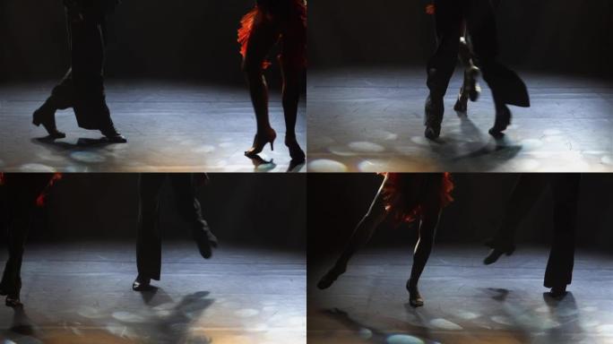 舞厅舞者表演的拉丁美洲舞蹈元素。伦巴，恰恰恰舞，在黑暗的工作室里用光线编排古典交际舞。轮廓。腿靠近。