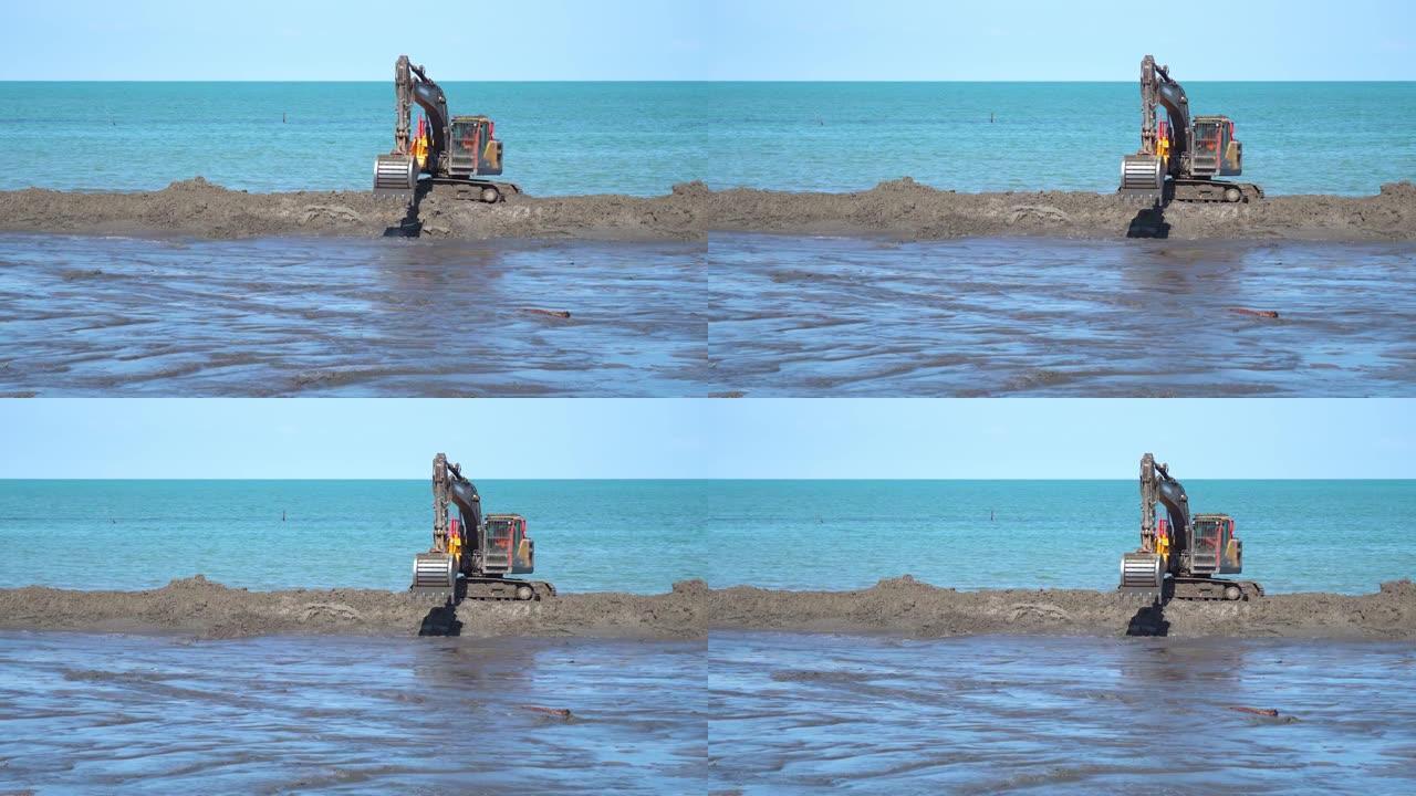 一辆挖掘机在蓝色大海前的沙丘上移动