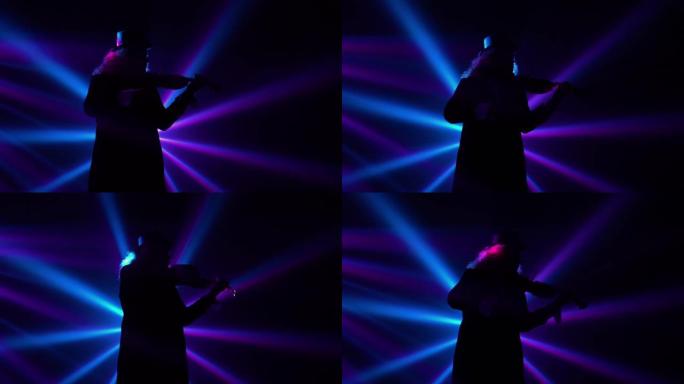 底视图小提琴演奏家在黑暗的工作室中演奏，闪烁着蓝色紫色光束。小提琴演奏，独奏会，现场表演，摇滚和古典