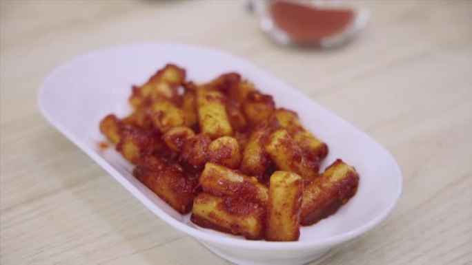 Tteokbokki年糕棒在桌子上的白色盘子上炒辣酱，韩国辣年糕棒特写