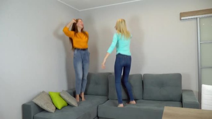 浅色和深色头发的女人一起在客厅的大沙发上跳跃。