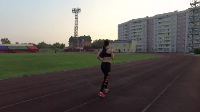 俄罗斯克麦罗沃-2018年7月11日: 慢动作。年轻女运动员在体育场跑步，戴着耳机听音乐
