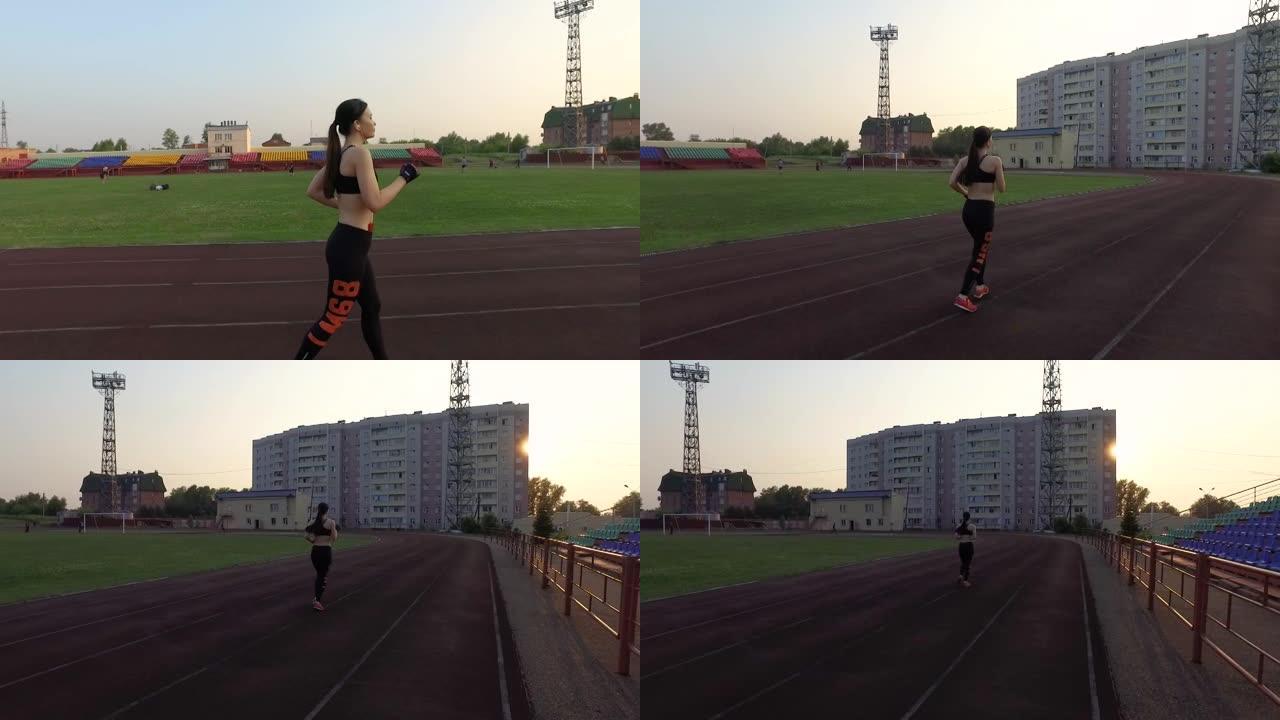 俄罗斯克麦罗沃-2018年7月11日: 慢动作。年轻女运动员在体育场跑步，戴着耳机听音乐