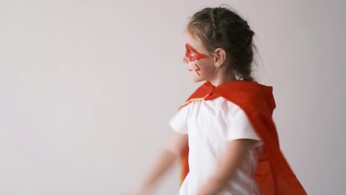 穿着红色斗篷的有趣的超级英雄小女孩。超级英雄概念。小孩子在孩子们中扮演英雄