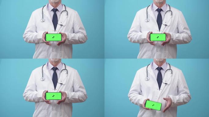 穿着医疗礼服的男士医生会显示带有应用程序的手机屏幕，特写镜头。听诊器制服的医生用手拿着电话，绿屏