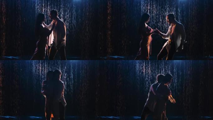 剪影恩爱的夫妇在舞蹈中旋转，紧紧触摸他们的身体并牵着手。在雨滴和蓝光的背景下，在黑暗的工作室里浪漫的