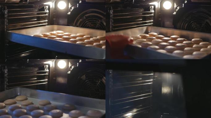 面包师打开烤箱门，取出煮熟的马卡龙。面包师在热食上使用硅胶手套