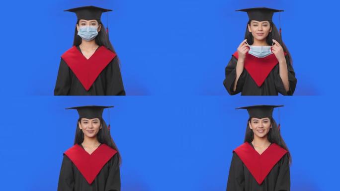 穿着帽子和长袍毕业服装的女学生肖像去除防护医用口罩。年轻的黑发女人在工作室摆姿势，蓝屏背景。特写。慢