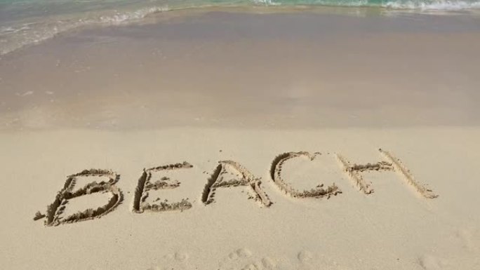 沙滩上带有海浪的沙滩铭文带有慢动作。假期和假期的概念