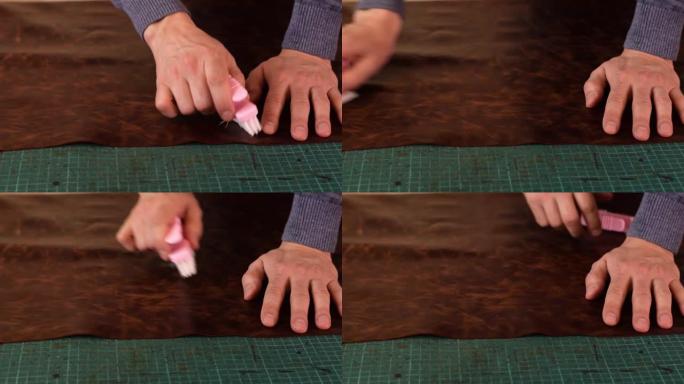 一个制革商的手的特写，刷一张棕色皮革，然后用手将其抚平。准备皮革进行切割。